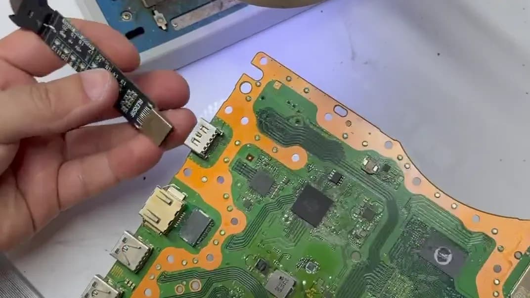 PS5-Mainboard in der Werkstatt: der HDMI-Port wird mit einem Diagnose-Tester geprüft, dessen Leuchtdioden die Verbindungen durchgehen