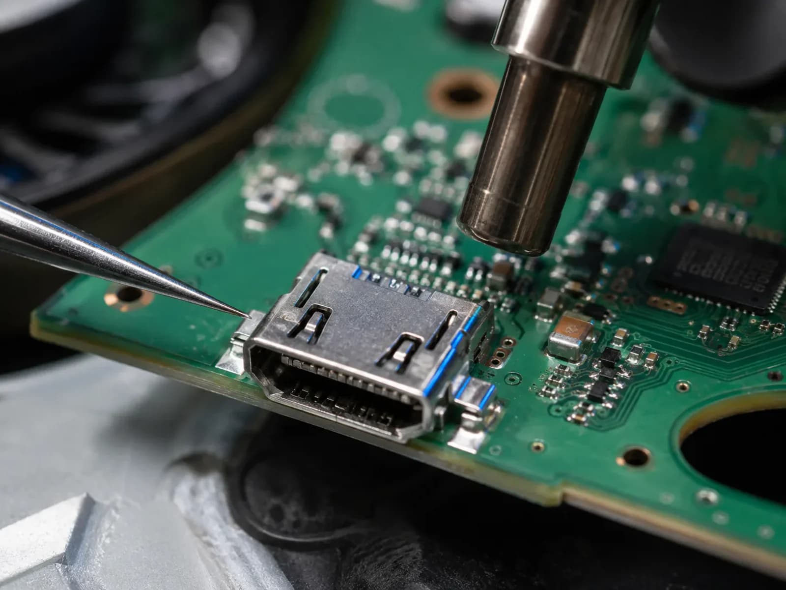 Makroaufnahme einer unbeschädigten HDMI-Buchse auf einer Konsolen-Platine. Die Lötstellen am Fuß der Buchse sind die Stelle, an der der Defekt entsteht – von außen ist davon nichts zu sehen.